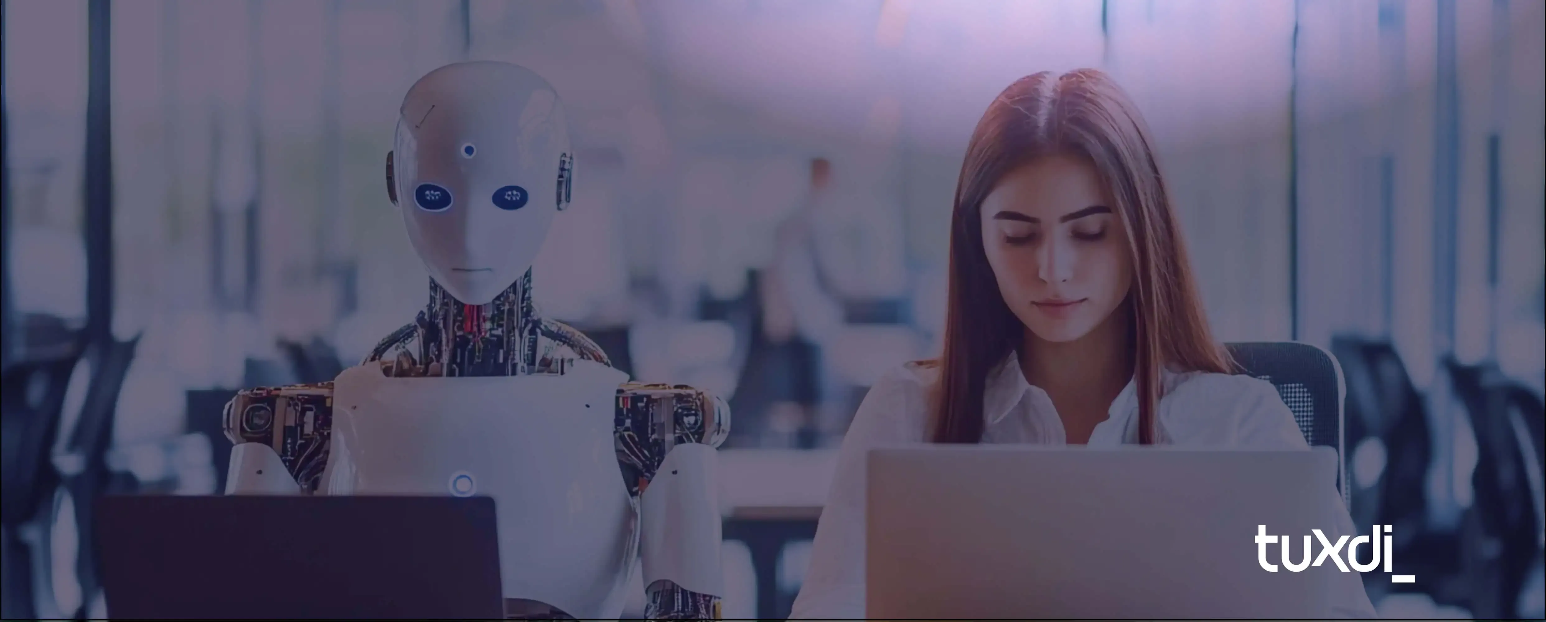 Woman working next to a humanoid robot in an office, both using laptops, symbolizing human–AI collaboration. Bright background with Tuxdi logo.